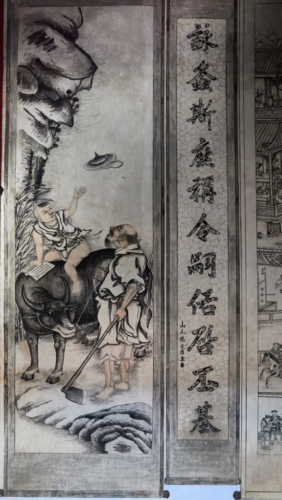 The image shows a detailed ink painting featuring a child sitting atop an ox and holding an open book. An older man stands beside them with a hoe, looking upwards. To the right, stylized Chinese characters form a vertical inscription in a separate section.